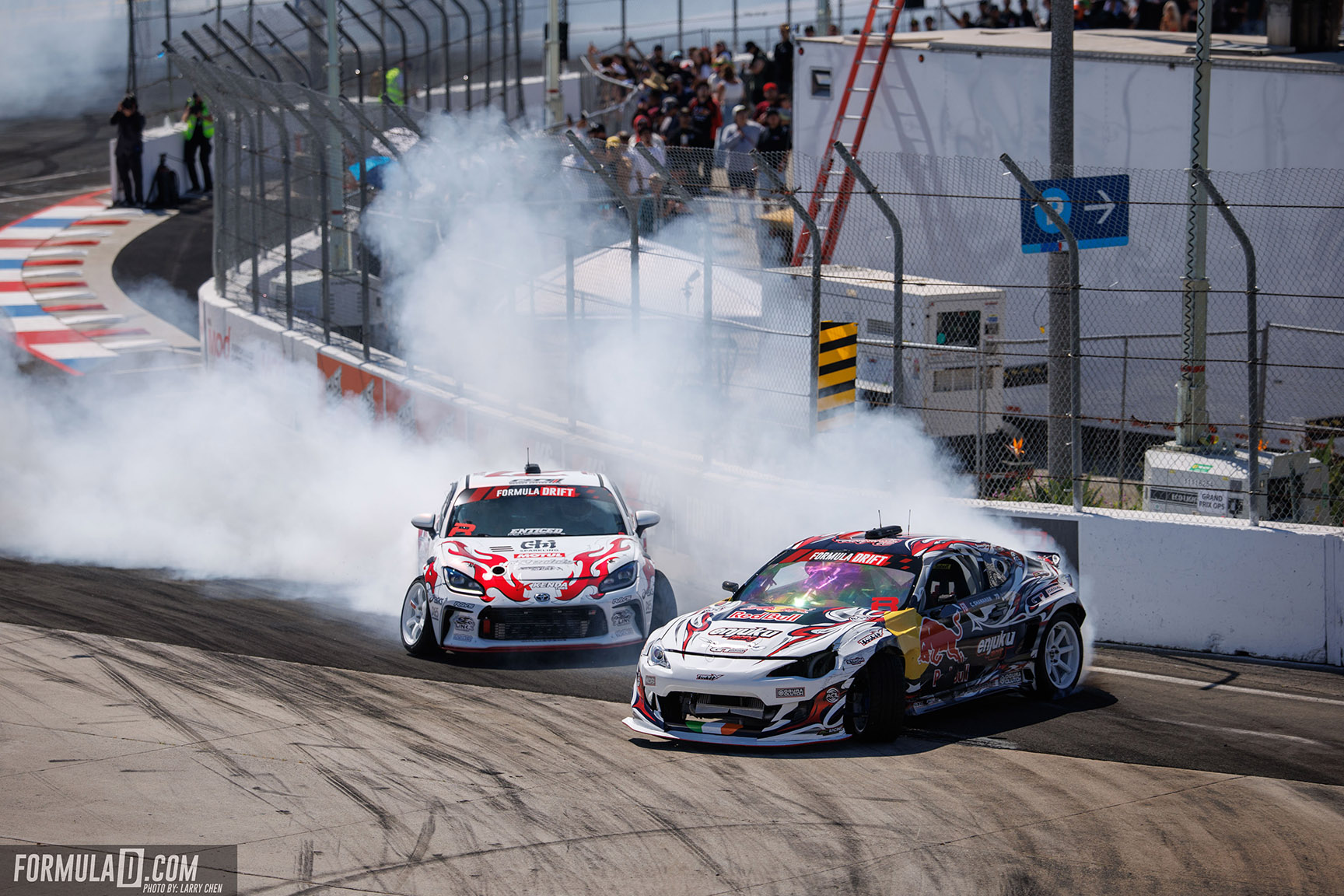 Conor Shanahan and Ken Gushi drift side-by-side near the wall during a close tandem battle.
