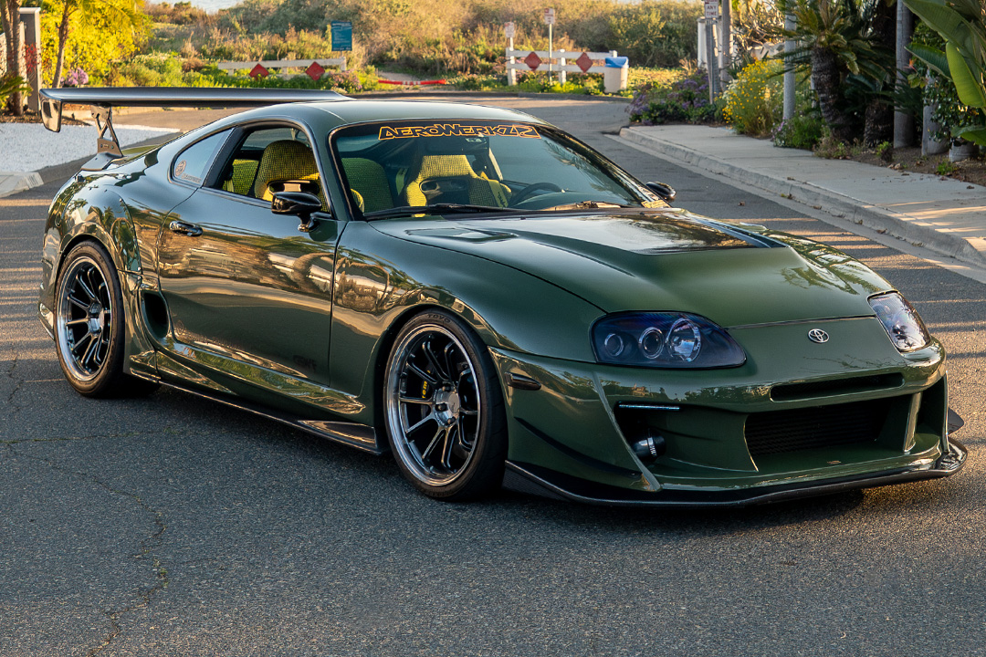 Leopold Barrit’s 1995 Toyota Supra parked near the waterfront featuring a Military Olive Green finish, Varis aero, and carbon GT wing.