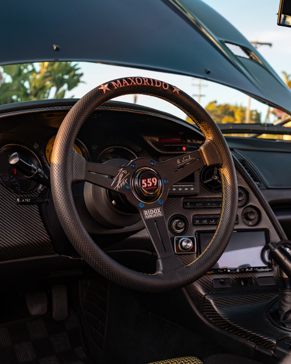 Interior view of Leopold Barrit’s 1995 Toyota Supra featuring a Max Orido x Nardi steering wheel and carbon fiber dashboard trim.