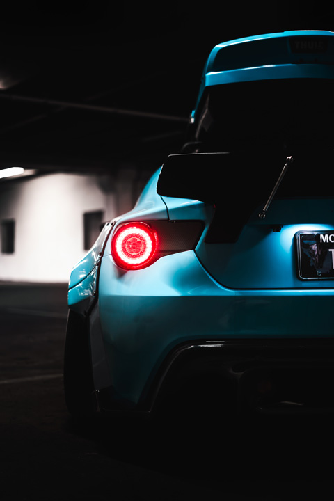 Custom widebody Scion FR-S with Rocket Bunny aero and roof-mounted ski box photographed inside a parking garage.