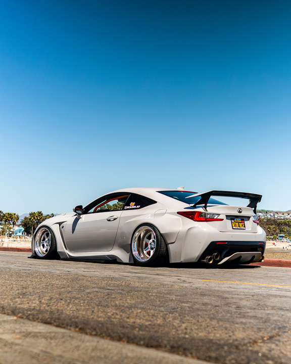 Rear three-quarter view of Dana Balthasar’s gray widebody Lexus RC F parked along the coast.