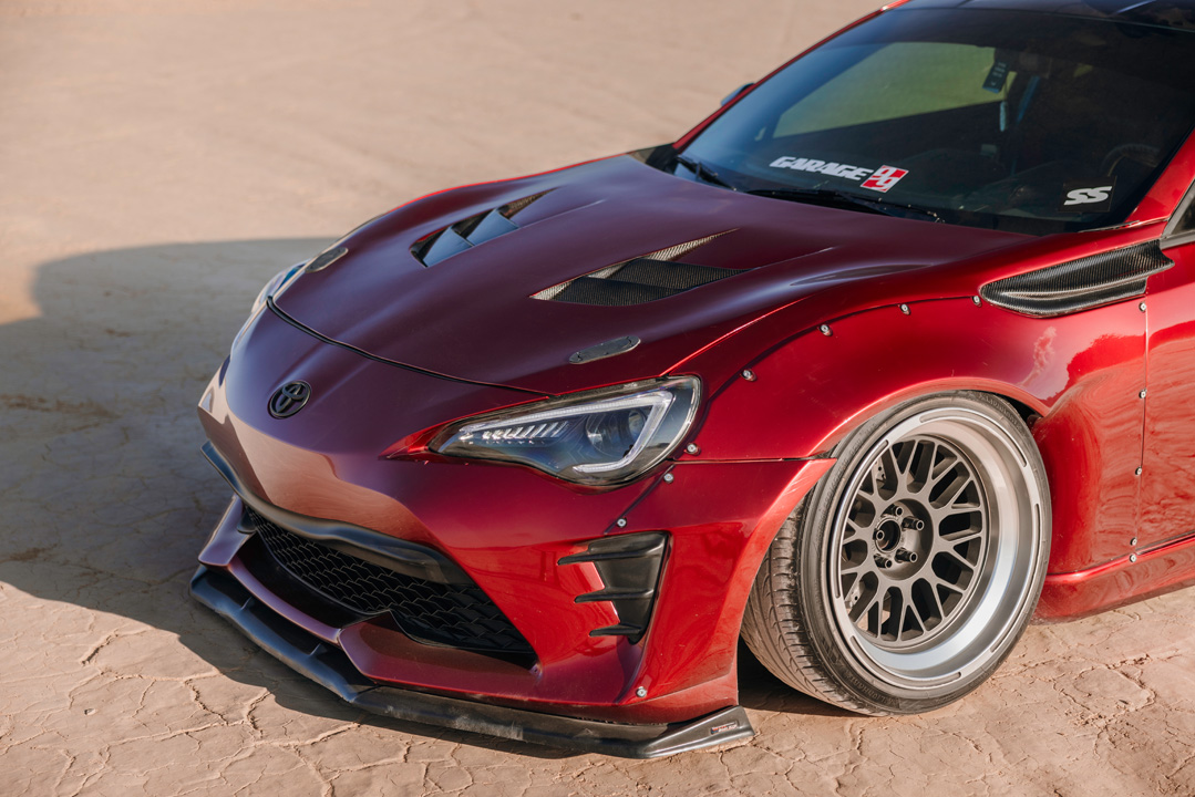 Front quarter detail of Anthony Gonzales’ red widebody Scion FR-S showing the carbon hood, aero kit, and Pandem wheels.