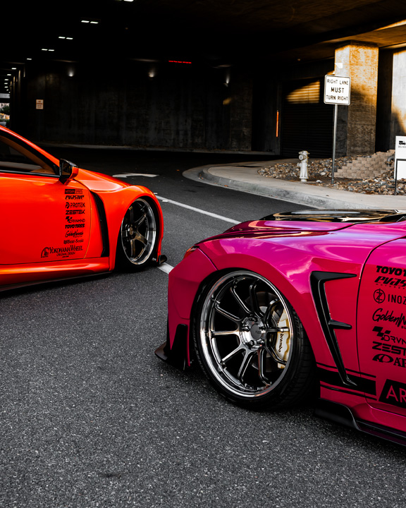Cassandra Balthasar’s orange Lexus LC500 and Giuseppe Balthasar’s pink Lexus IS 500 parked together under an overpass.