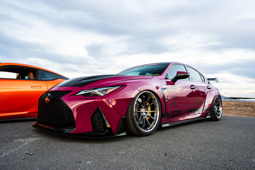 Front three-quarter view of Giuseppe Balthasar’s pink widebody Lexus IS 500 parked beside Cassandra Balthasar’s orange Lexus LC500.