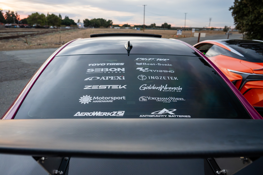 Rear window sponsor decals on Giuseppe Balthasar’s Lexus IS 500 with Cassandra Balthasar’s orange Lexus LC500 in the background.