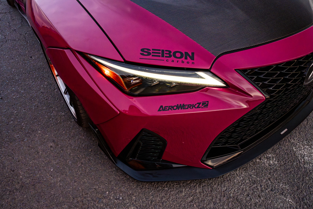 Front headlight detail of Giuseppe Balthasar’s pink Lexus IS 500 with Seibon carbon hood and Aerowerkz decal.