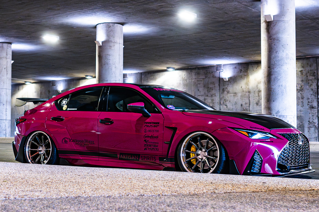 Side view of Giuseppe Balthasar’s pink widebody Lexus IS 500 under a concrete overpass.