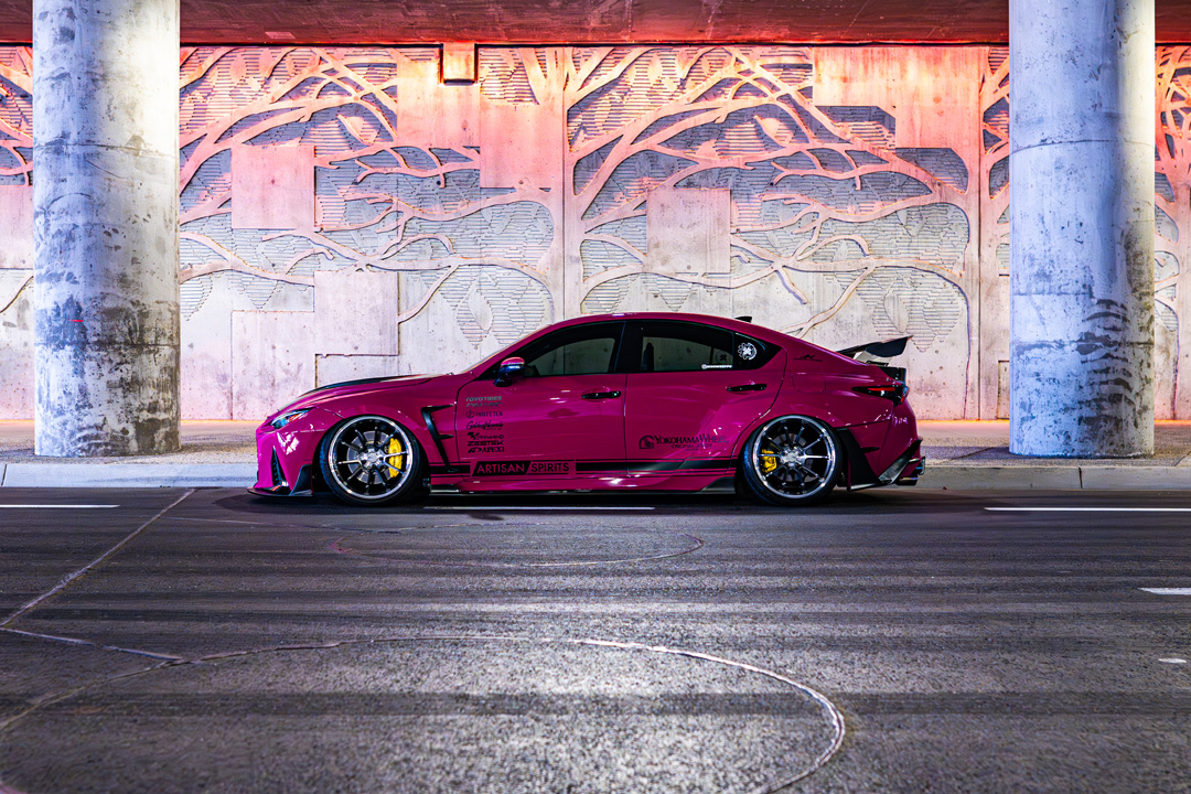 Side profile of Giuseppe Balthasar’s pink widebody Lexus IS 500 under a lit concrete overpass.