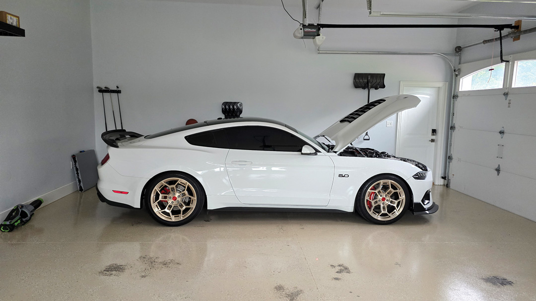 Side profile of William Howard's white 2018 Ford Mustang GT in a garage with the hood open.