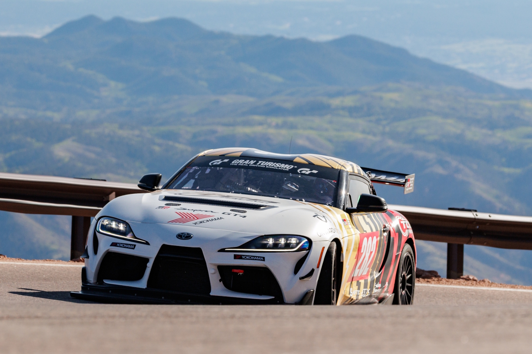 Laura Hayes driving a Yokohama-backed Toyota Supra GT4 at Pikes Peak with mountain scenery in the background.