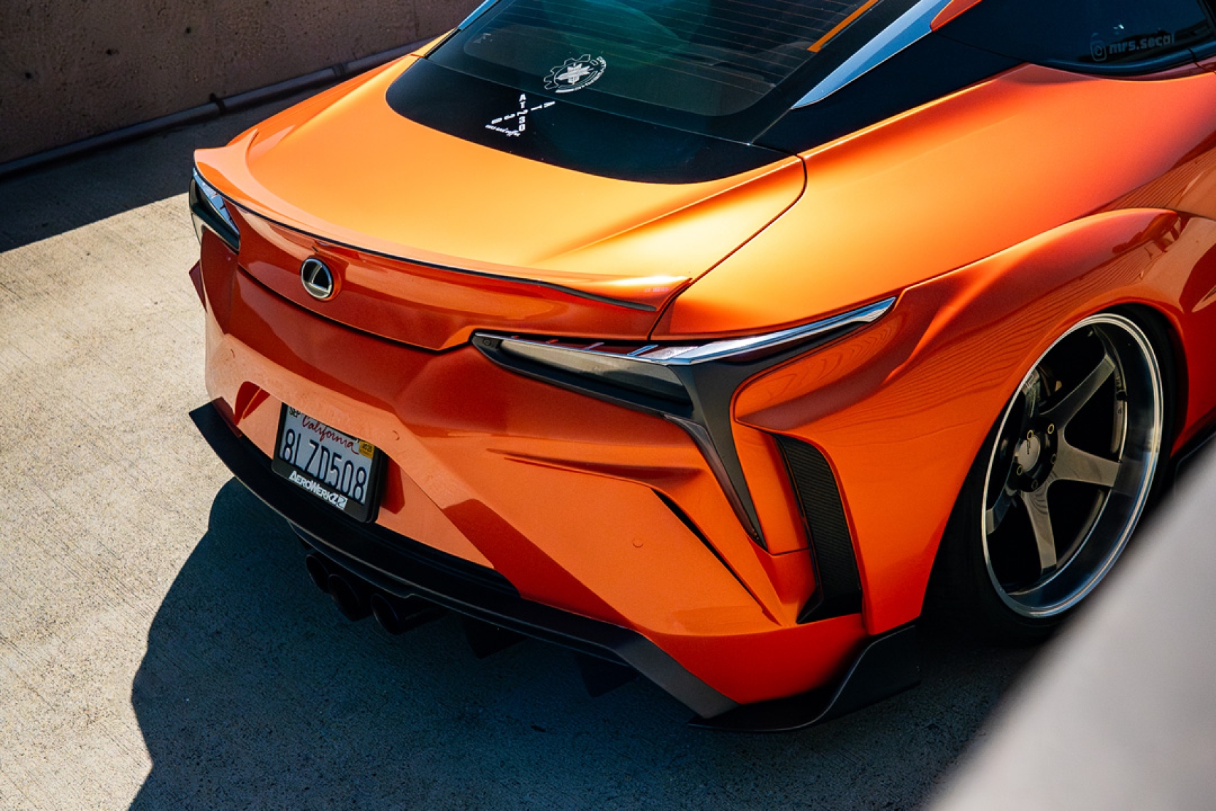 Cassandra Balthasar’s orange widebody Lexus LC500 parked above the ocean in a front three-quarter view.