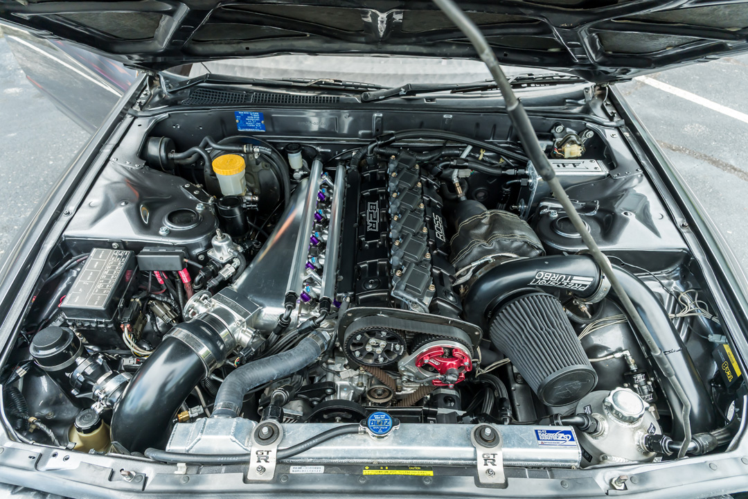 Engine bay detail of Cee Vann’s 1990 Nissan Skyline GT-R showing the billet RB30 setup, Precision turbo, Hypertune intake manifold, and Haltech-managed hardware.