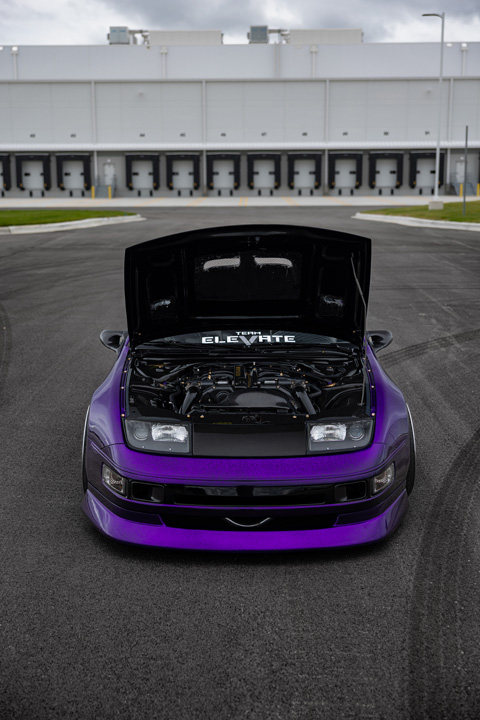 Front view of Alex Hammond’s purple 1993 Nissan 300ZX Convertible with the hood open, showing the engine bay, low stance, and Team Elevate windshield banner.