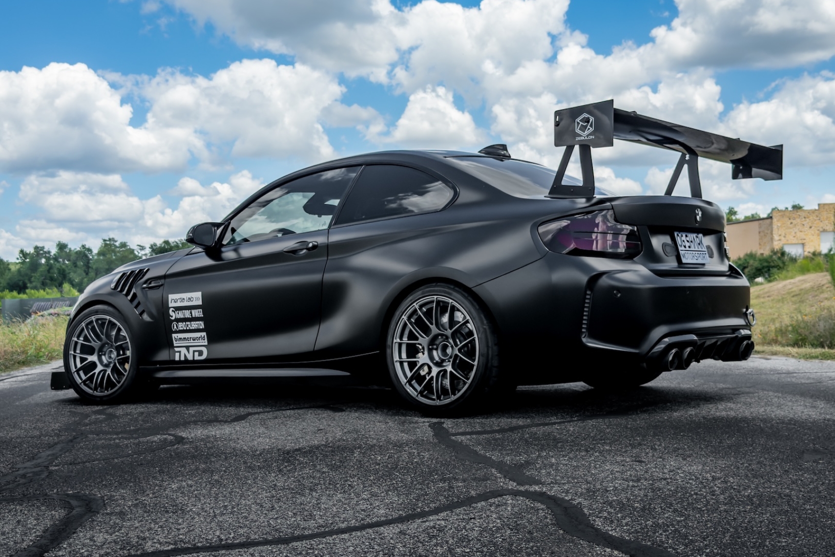 Jason Merck’s black 2020 BMW M2 with Zebulon rear wing and track aero parked under a cloudy sky.