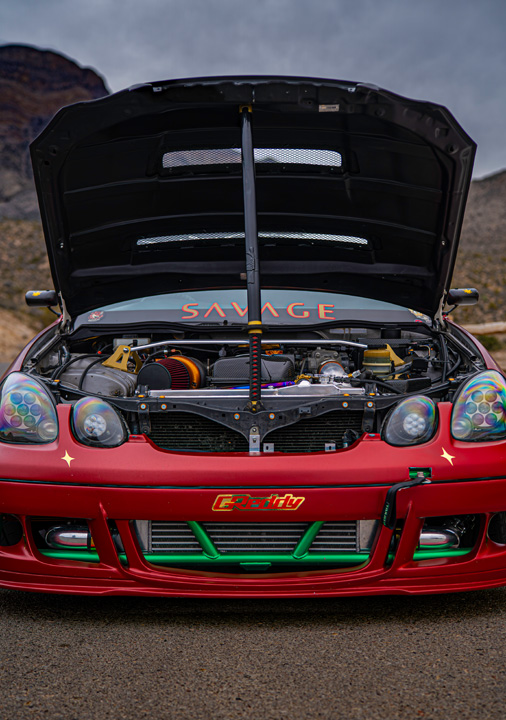 Chris Burch’s satin red 1997 Toyota Aristo with RAW livery, turbocharged 2JZ power, 8HP70 transmission swap, Advan RG4 wheels, Big Country Labs wing, and function-first street build details.