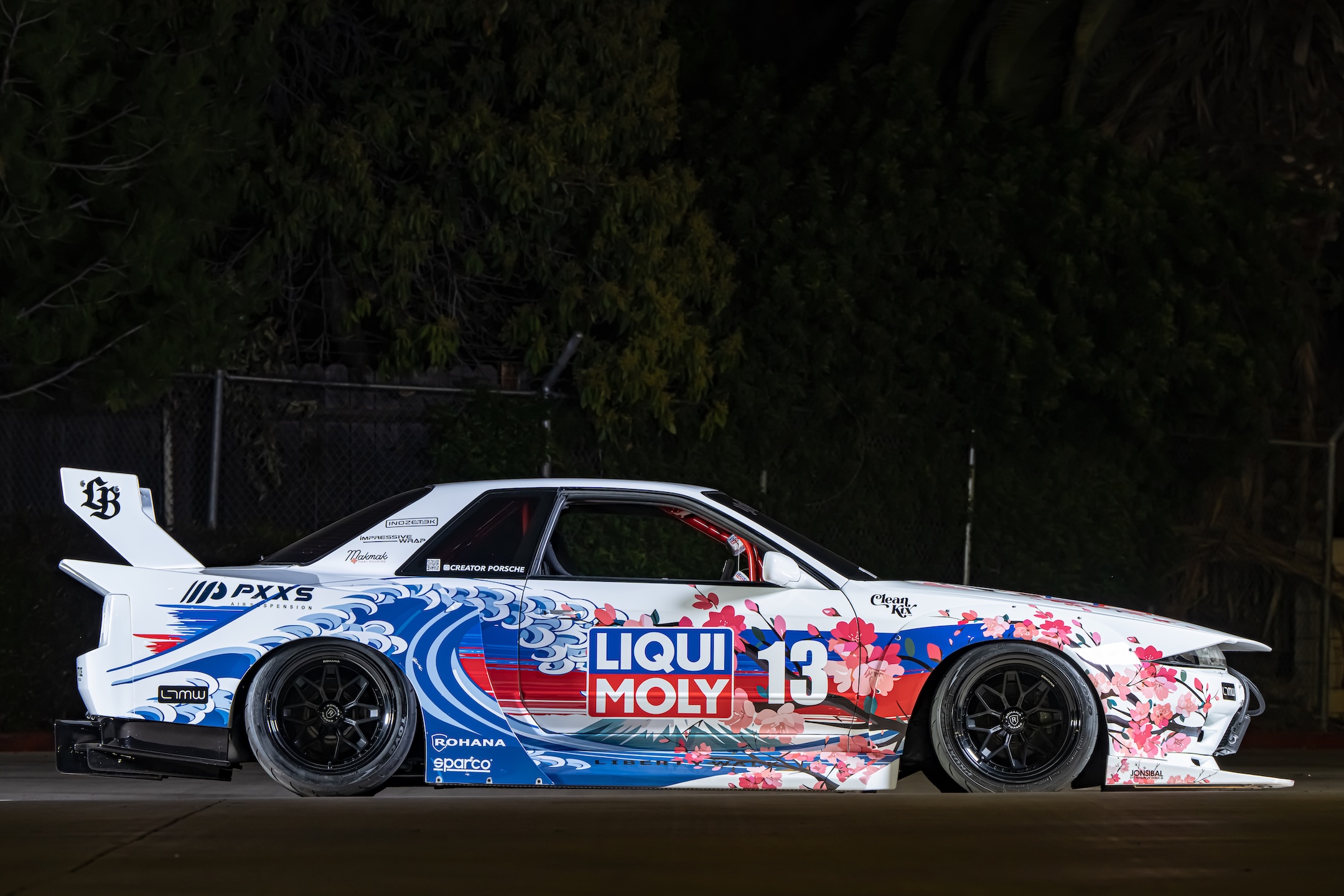 Side profile of Osmond Seangsuwan’s 1990 Nissan Skyline GT-R showing the Liberty Walk LB-Kaido widebody kit, LIQUI MOLY livery, Rohana wheels, Prazis air suspension, and Japanese-inspired wave and cherry blossom artwork.