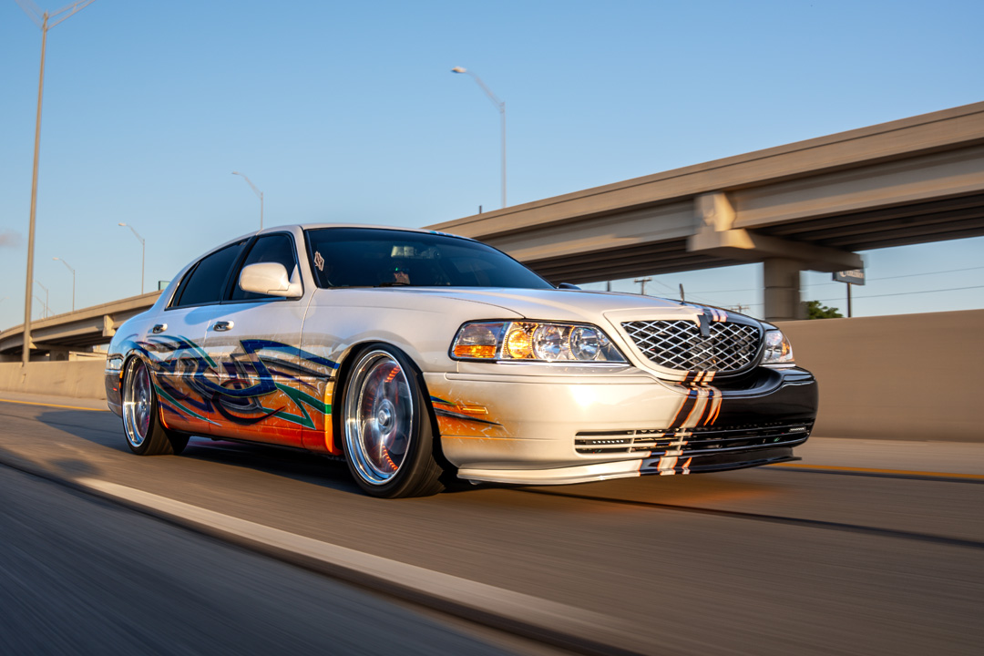 Sam Benischek’s 2006 Lincoln Town Car Signature Limited with custom Two-Face graphic paint, low air suspension stance, KRNC forged wheels, custom interior, trunk setup, and full-size luxury sedan styling.
