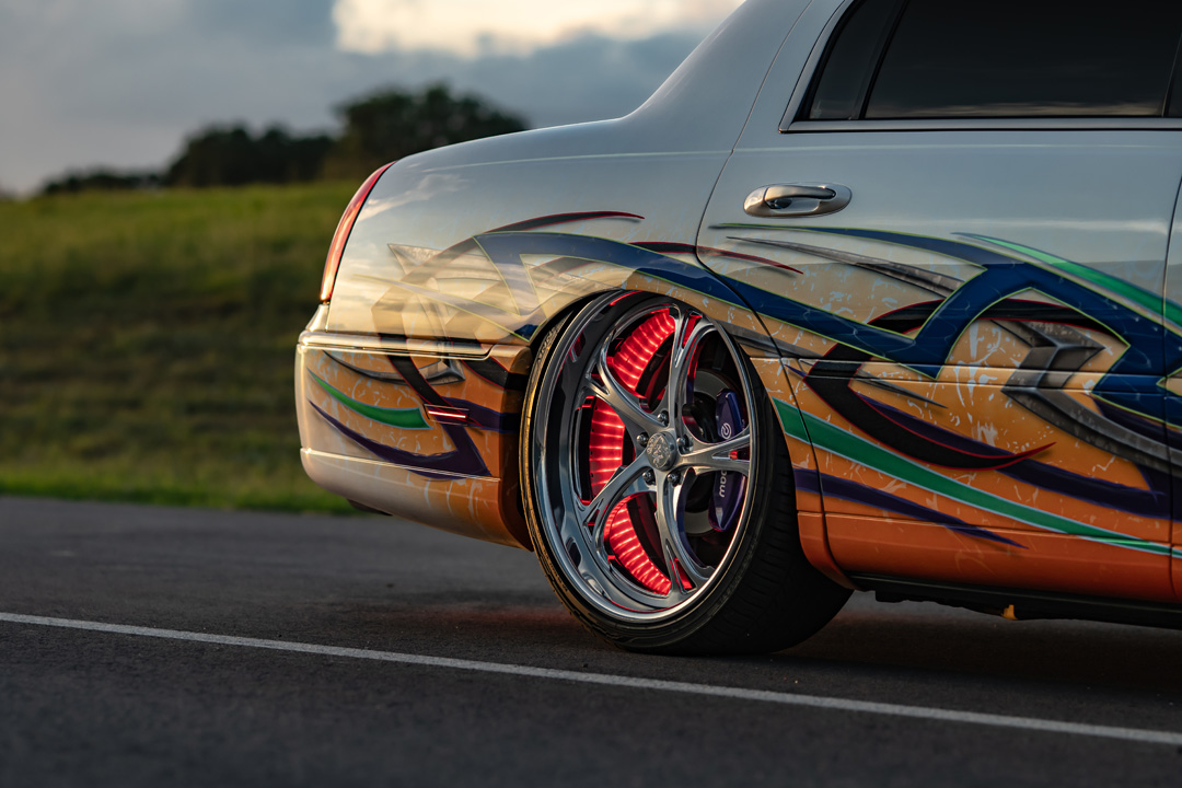 Sam Benischek’s 2006 Lincoln Town Car Signature Limited with custom Two-Face graphic paint, low air suspension stance, KRNC forged wheels, custom interior, trunk setup, and full-size luxury sedan styling.