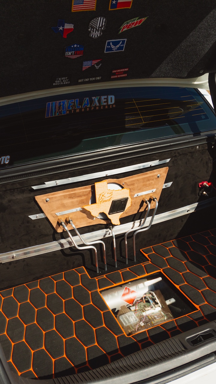 Custom trunk detail of Sam Benischek’s 2006 Lincoln Town Car showing the false trunk floor, hardline air suspension setup, Texas-themed switch panel, Relaxed Atmosphere decal, and custom upholstery.