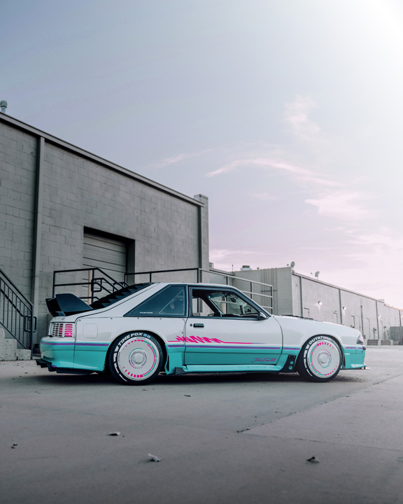 Regan McLaughlin’s 1988 Ford Mustang GT TimeFox with custom multi-tone paint, Ford Barra turbo swap, wide fiberglass fenders, retro Foxbody styling, HaloBLK wheel covers, custom interior, and nostalgic audio details.