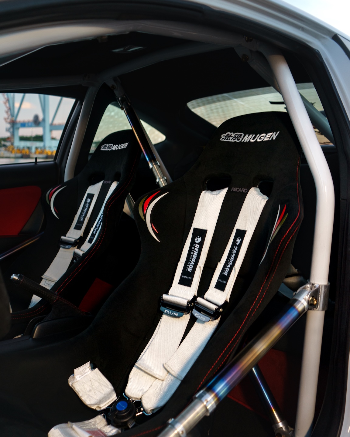Interior detail of Jonathan Ortiz’s 2005 Acura RSX Type-S showing the Mugen MRZ bucket seats, Willans Renegade harnesses, Cusco roll cage, titanium door bar, and DC5R interior conversion.