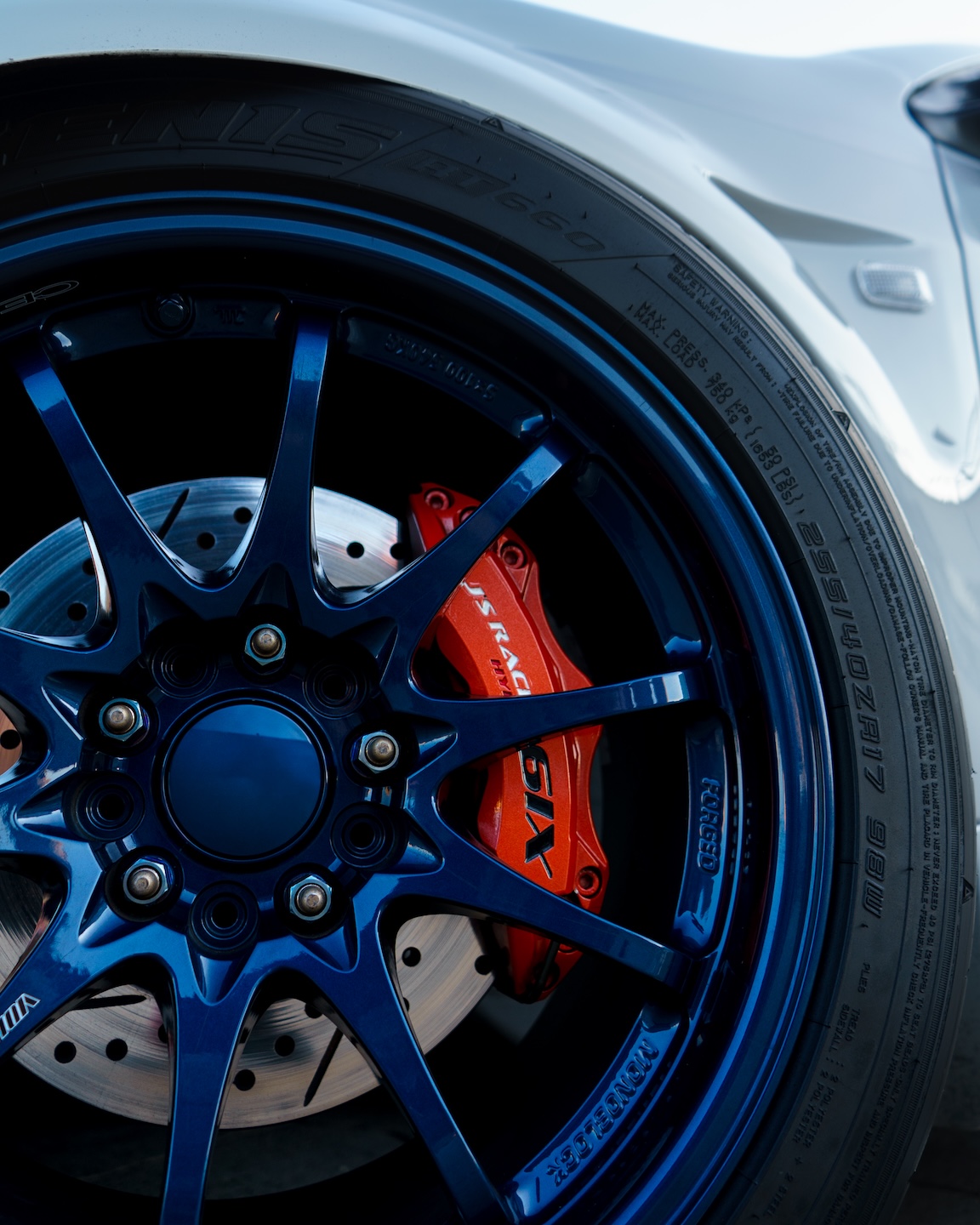 Close-up wheel and brake detail of Jonathan Ortiz’s 2005 Acura RSX Type-S showing the blue Volk Racing CE28N wheel, Falken RT660 tire, J’s Racing Hyper Six caliper, and StopTech rotor.