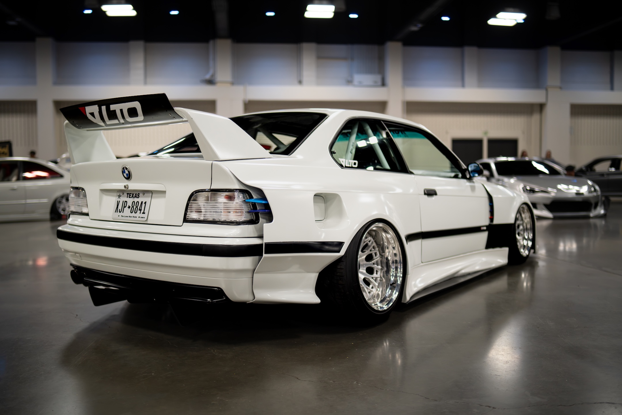 White widebody BMW E36 displayed on the show floor during IMPORTEXPO Texas 2026.