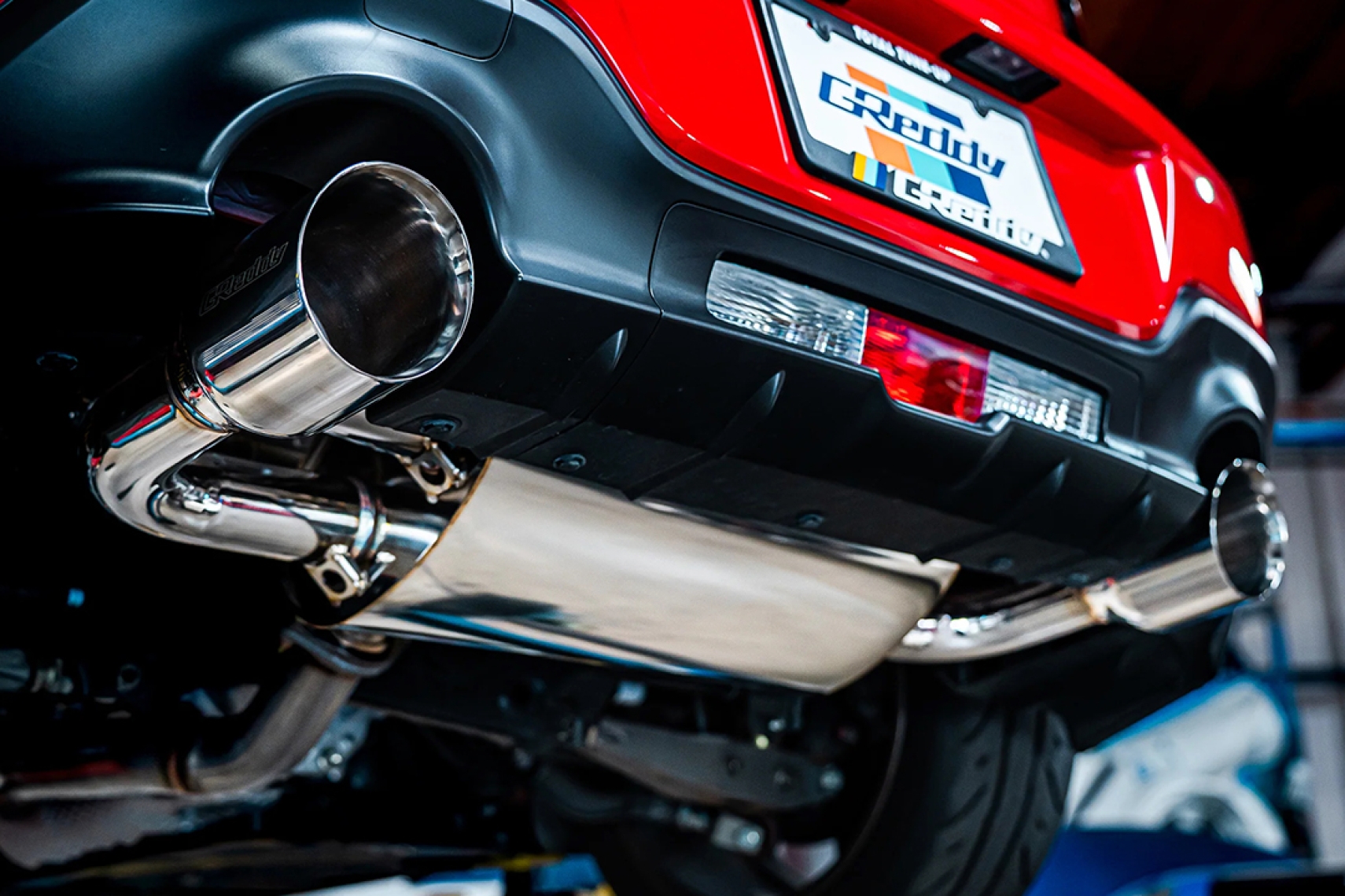 GReddy Supreme SP cat-back exhaust installed on a Toyota GR86 with dual polished exhaust tips visible under the rear bumper.