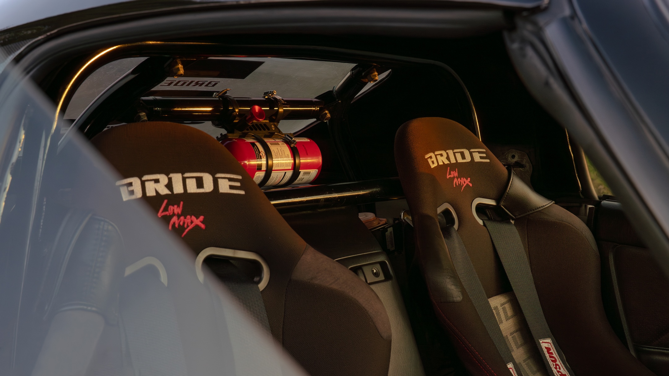 Interior detail of Thomas Wu’s 2002 Honda S2000 showing the Bride Gias bucket seats, six-point harnesses, Cusco roll cage, fire extinguisher, and track-focused cabin.