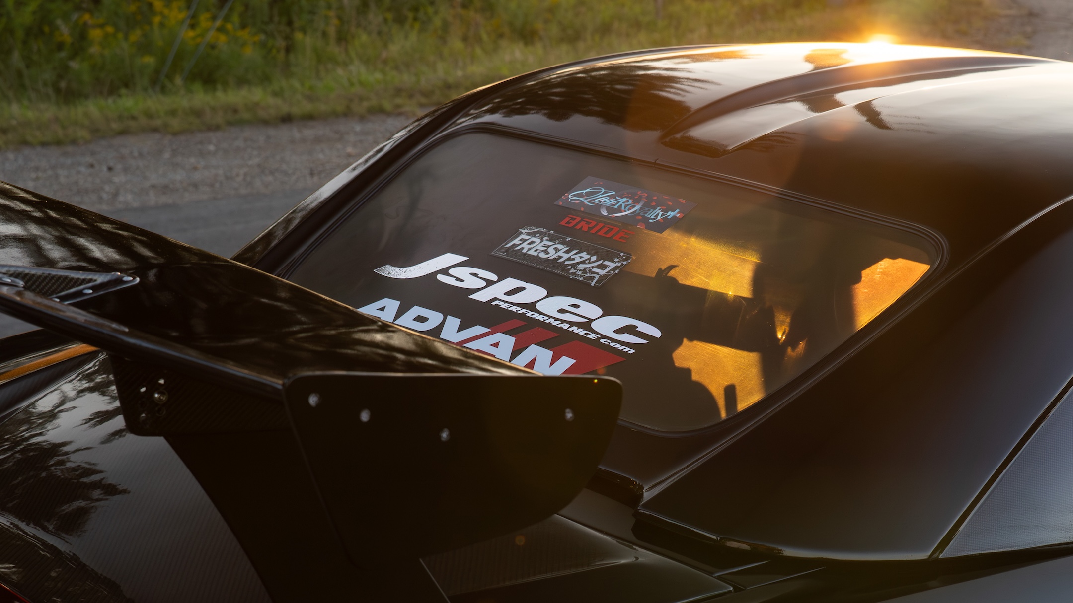 Rear aero detail of Thomas Wu’s black 2002 Honda S2000 showing the Type-5-style rear wing, hardtop, rear glass decals, and golden-hour reflections.