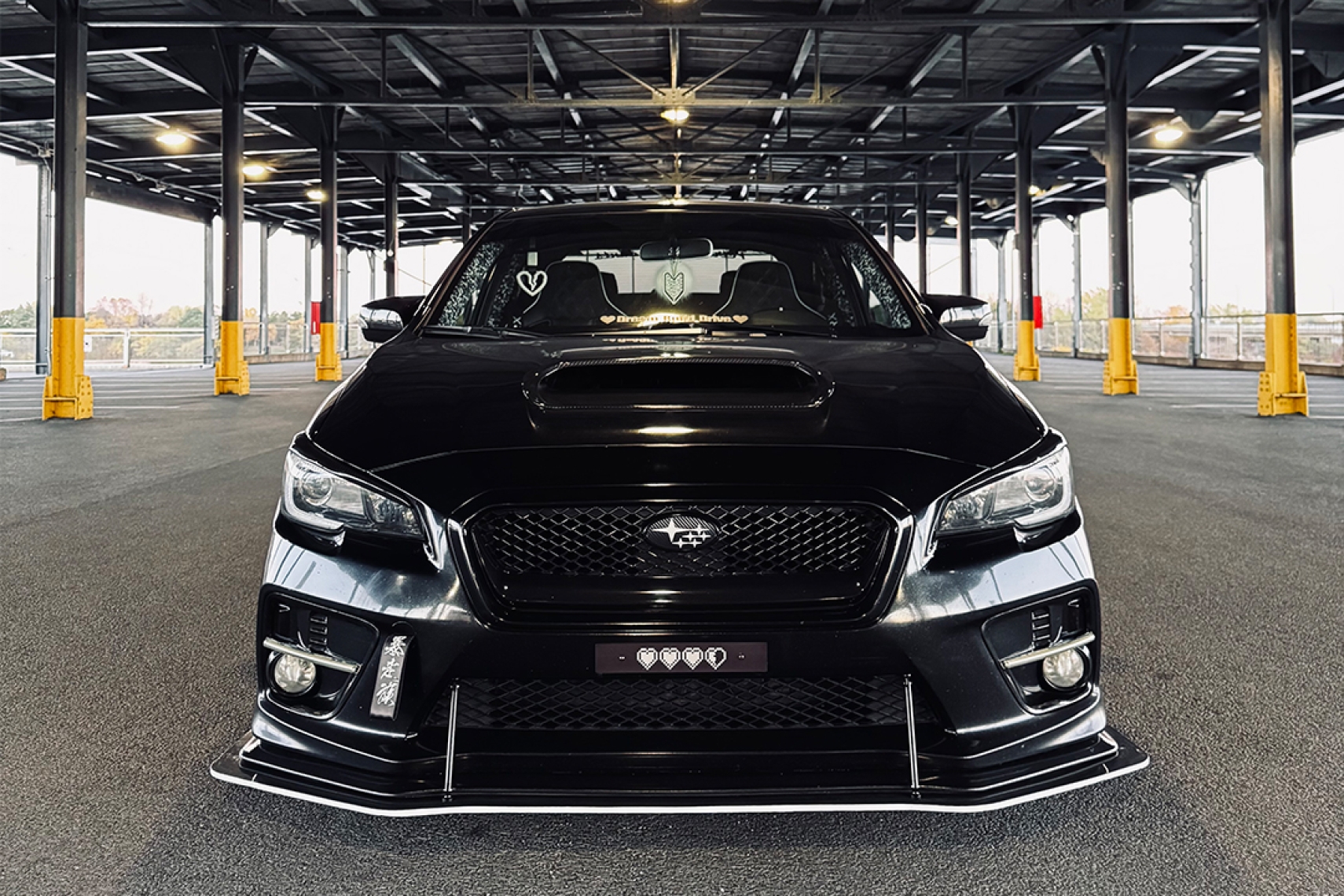 Front view of Melissa Pelletier’s 2017 Subaru WRX showing its black-and-white theme, ADE Creations front splitter, JDM grille, carbon fiber accents, and lowered stance.