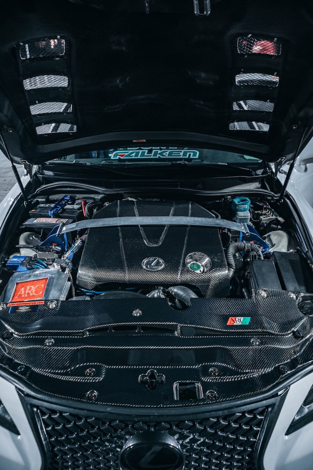 Engine bay of Harry Nguyen’s 2006 Lexus IS350 showing its carbon-fiber engine cover and radiator shroud, ARC intake box, and Cusco strut bar.