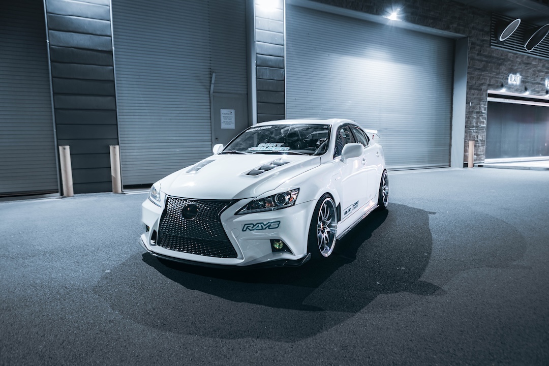 Front three-quarter view of Harry Nguyen’s 2006 Lexus IS350 showing its third-generation front-end conversion, carbon-fiber hood and fenders, AIMGAIN front lip, and Volk Racing LE28N wheels.