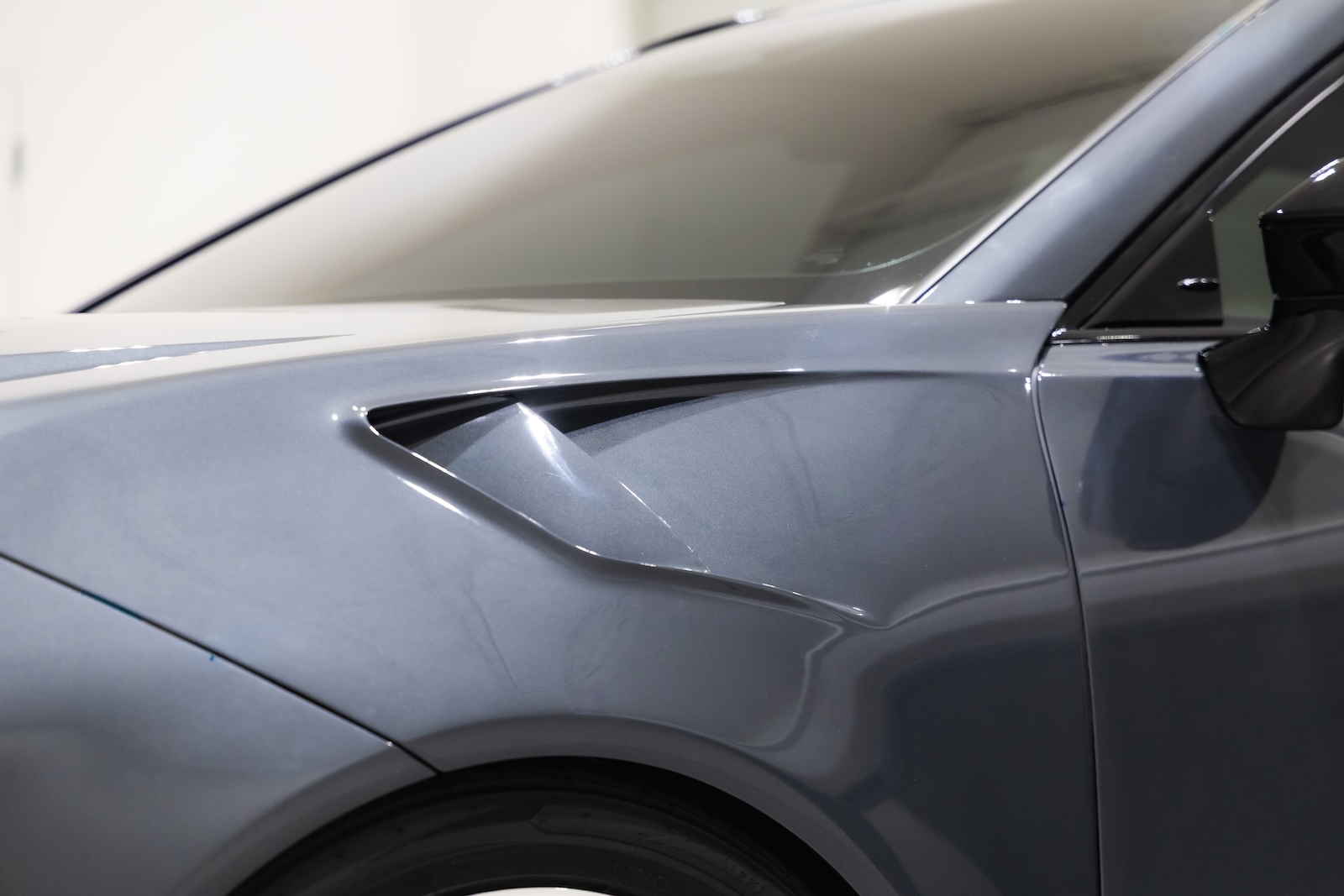 Close-up of the Toyota Crown Signia GT-S Concept's custom widebody front fender, featuring sculpted bodywork, an integrated vent and dark gray metallic paint.